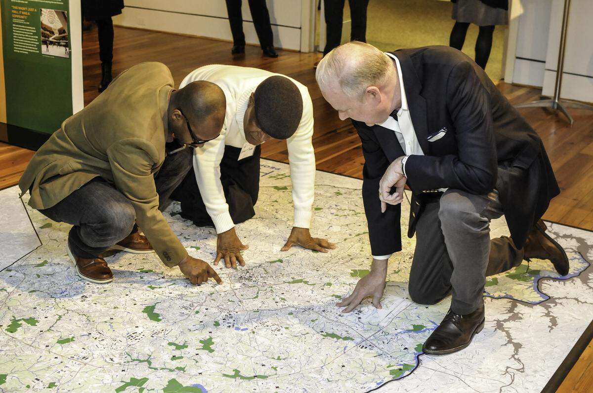 Levine Museum historian, Willie Griffin, (left) works with Everett Taylor (center) and Dan Spock at the opening of the #HomeCLT exhibit to find Taylor’s childhood neighborhood, University Park, on a map.