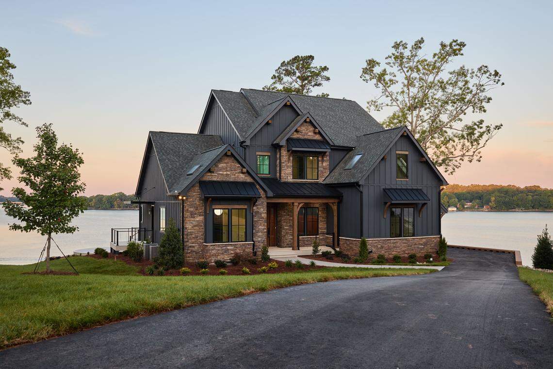 A high-quality, wide-angle exterior photo of the HGTV Dream Home 2026 at twilight, showcasing its waterfront setting.