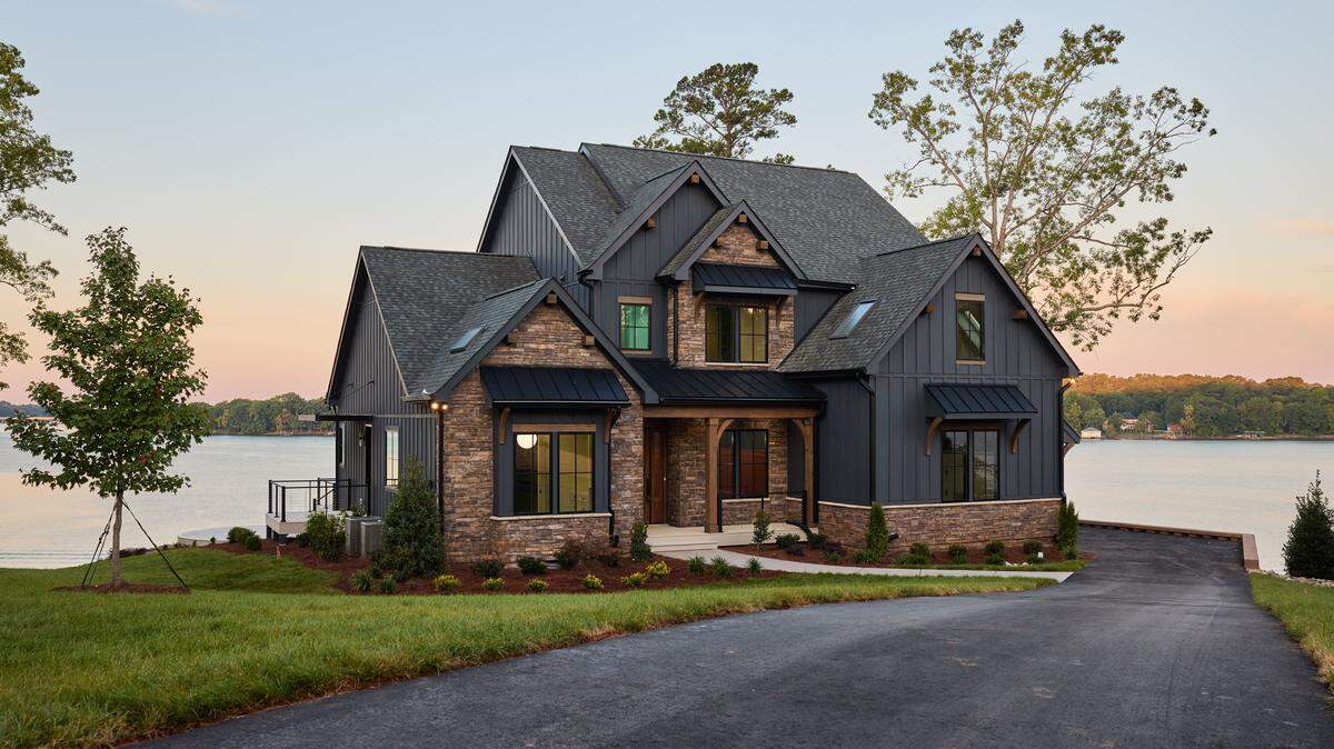 A high-quality, wide-angle exterior photo of the HGTV Dream Home 2026 at twilight, showcasing its waterfront setting.