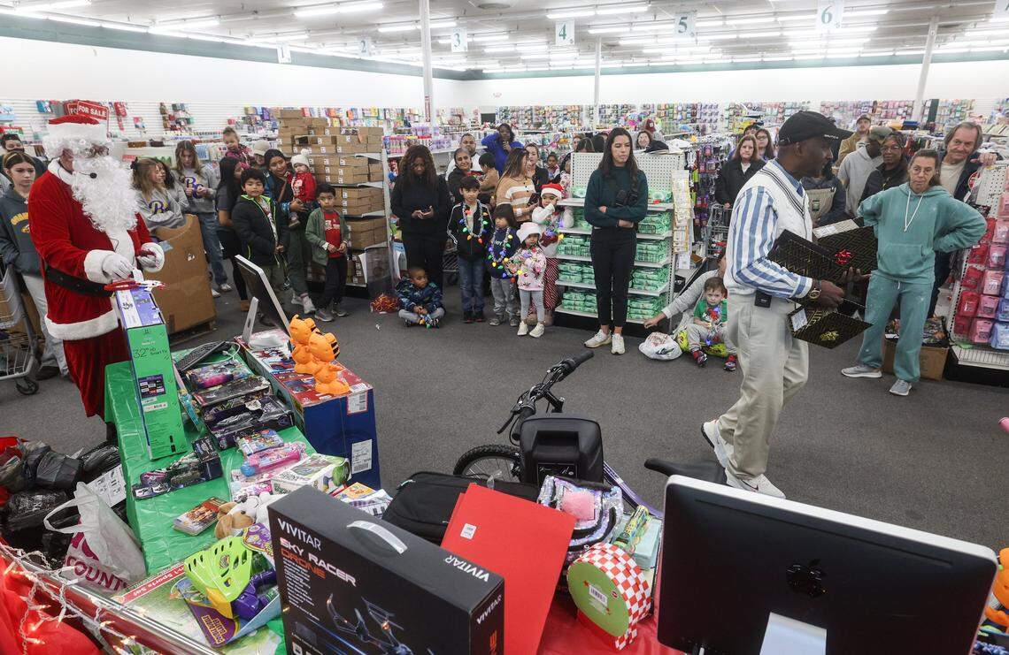 Close to a hundred people attend a secret santa gift giveaway at Mighty Dollar in Gastonia, hosted by Joe Mayes, far left, and friend, Tim Greene, on Friday, December 12, 2025.