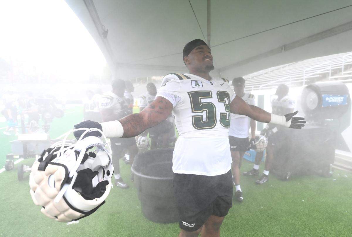 Charlotte 49ers defensive lineman Austin Fontaine enjoys the mist from a fan during a break in the team’s first practice on Friday, August 4, 2023.