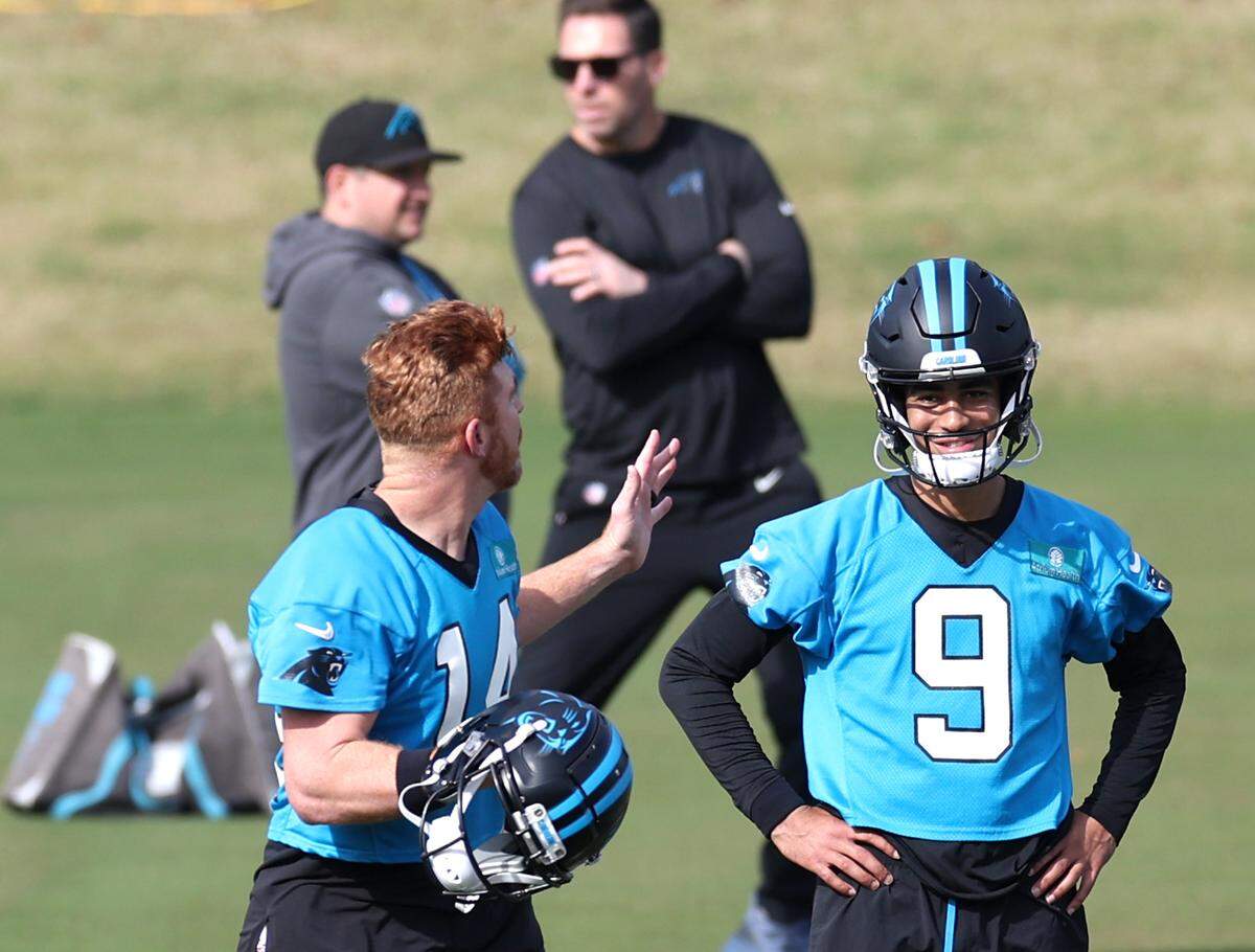 Carolina Panthers quarterback Bryce Young, right, smiles as quarterback Andy Dalton, left, speaks to him during practice on Monday, November 18, 2024.