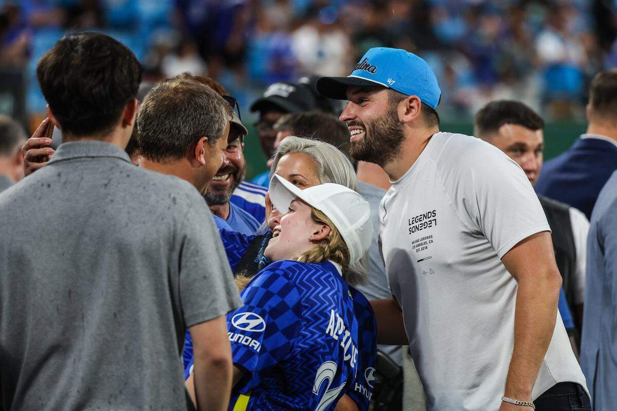 Newly signed Panthers quarterback Baker Mayfield, far right, poses for photos with fans on the sidelines ahead of the match between Charlotte FC and Chelsea FC at Bank of America Stadium on Wednesday, July 20, 2022 in Charlotte, NC.