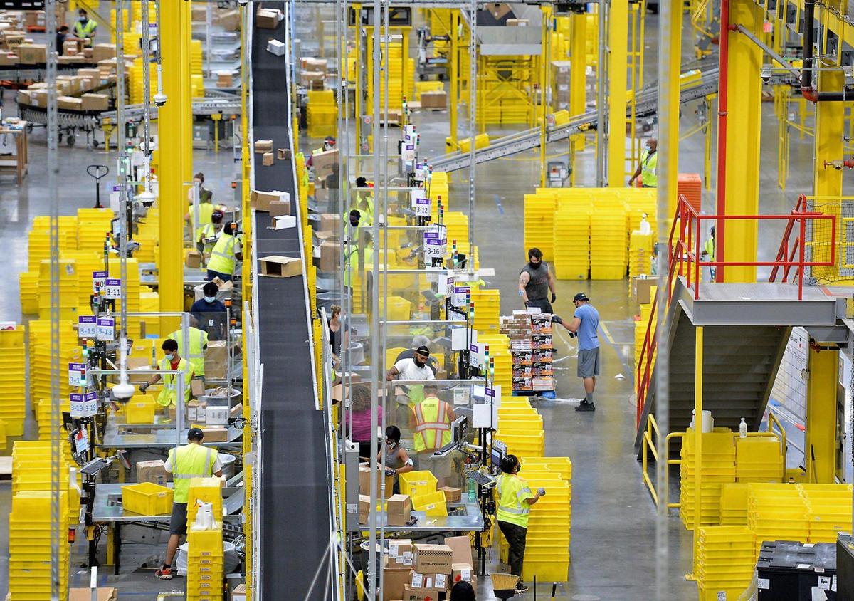 Employees at Amazon’s CLT4 West Charlotte fulfillment center handle packages and merchandise July 1. The center has setup numerous safety measures amid the COVID-19 crisis. Among the measures are temperature checks and thermal cameras, distribution of masks, gloves, hand sanitizer, mobile hand washing stations, disinfectant spraying and social distancing, as well as adding Plexiglas between stations.
