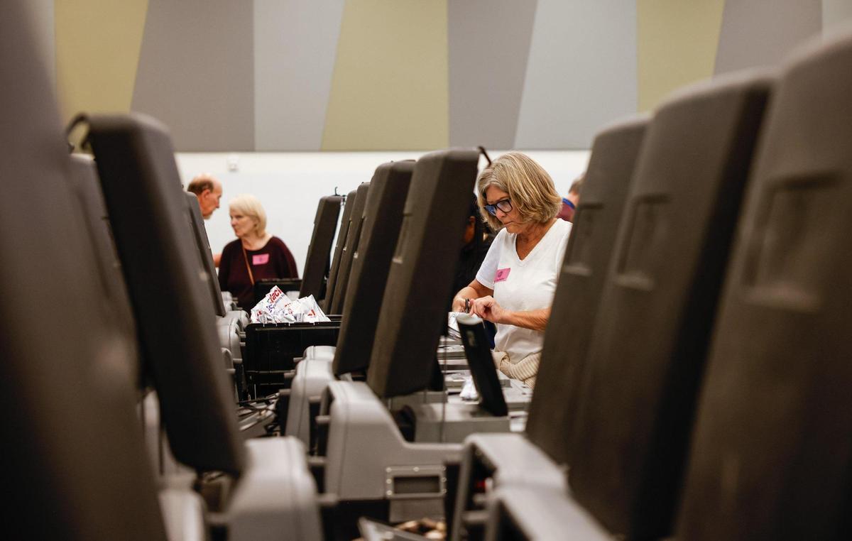 Volunteers feed ballots into ballot machines.