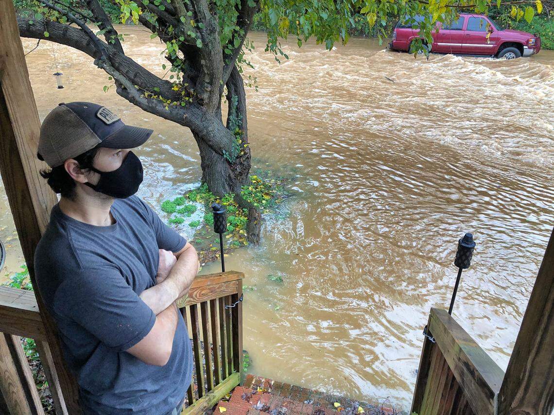 Edmar Simoes stands on his front porch watching flood waters pass by his home on Spruce St. in Charlotte, NC on Thursday, November 12, 2020.