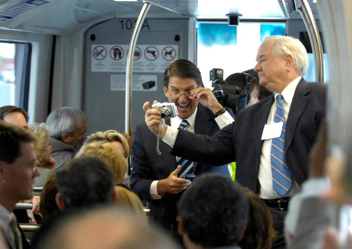 Charlotte Mayor Pat McCrory, left, laughs as he looks at a photo taken by Mecklenburg County Commissioner Parks Helms, right, while riding on the Lynx Blue Line train on Monday morning in November 12007