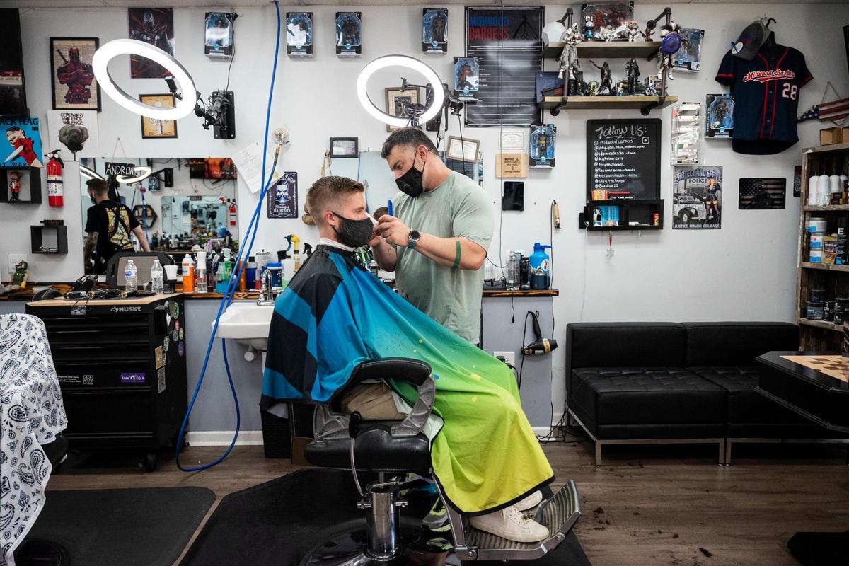 Joseph Marsala known “Joey the Barber” cuts Trevor Cockerham’s hair at the barber shop he owns, Midwood Barbers, on Wednesday, Aug. 18, 2021 in Charlotte, NC. On the mask mandate, Marsale says “we don’t talk about politics or religion in here.”