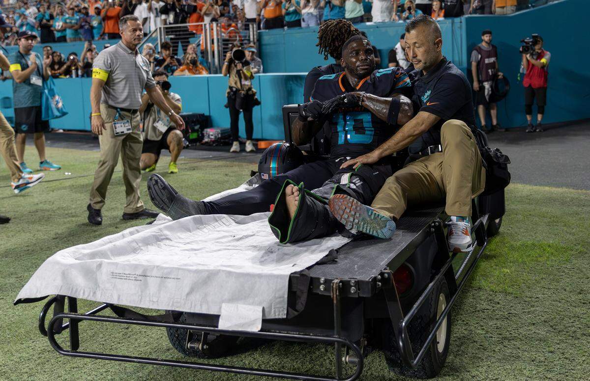 Miami Dolphins wide receiver Tyreek Hill sits next to associate athletic trainer Naohisa Inoue as he is carted off the field after suffering a dislocated knee Monday. Hill had surgery and will miss the rest of the season.