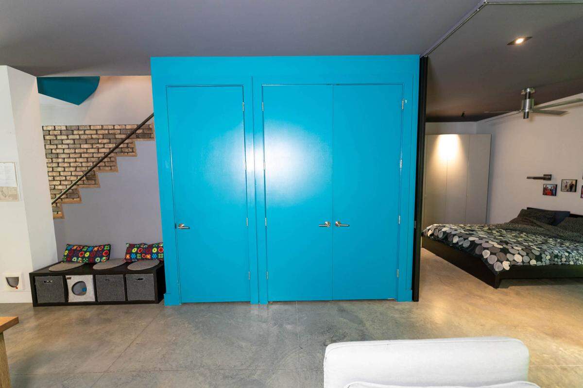 Toby Witte’s master bedroom can be walled off with a recessed sliding wall next to this large blue laundry and storage area. When it’s closed, it simply appears as a blue accent where four rooms come together.