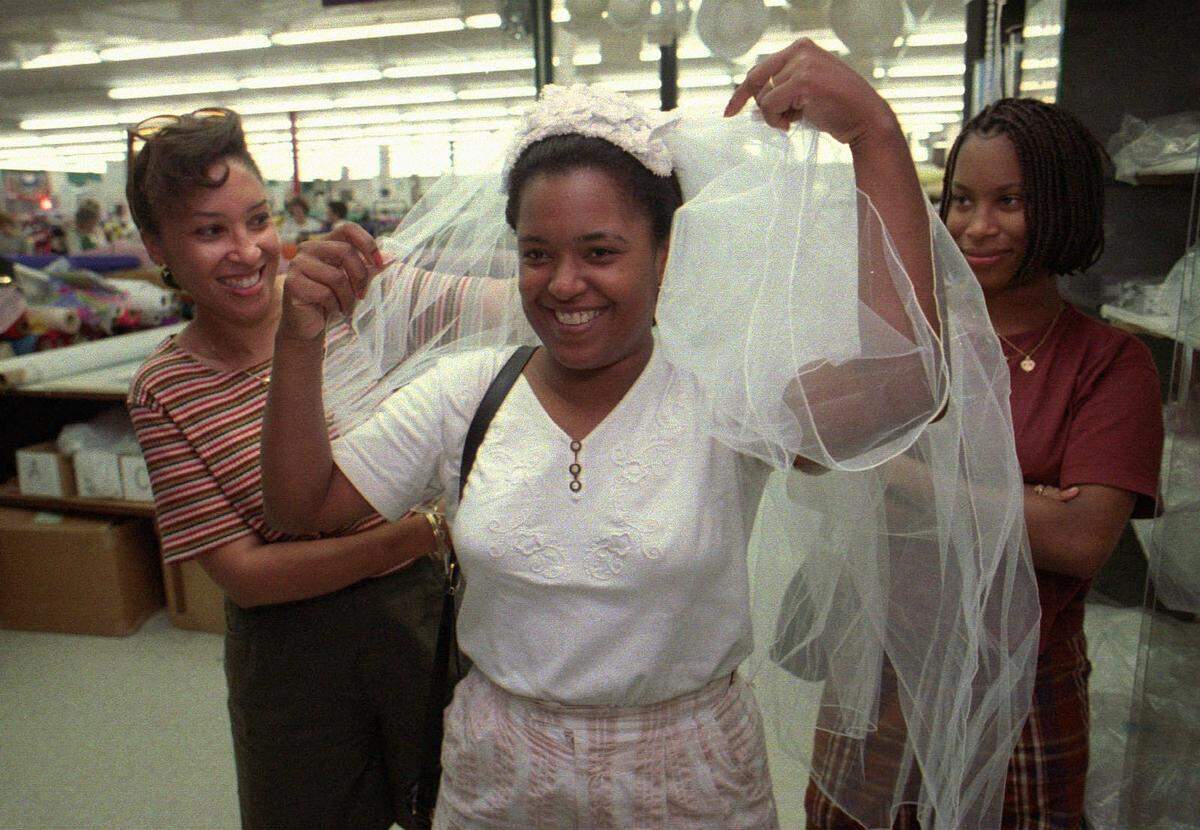 Chineta Smith of Gaffney tries on bridal veil fabric at Mary Jo’s Cloth Store in 1995. Helping her are cousins J’Melle Hargrove (left) and Rasheeda Ali, both of Atlanta.