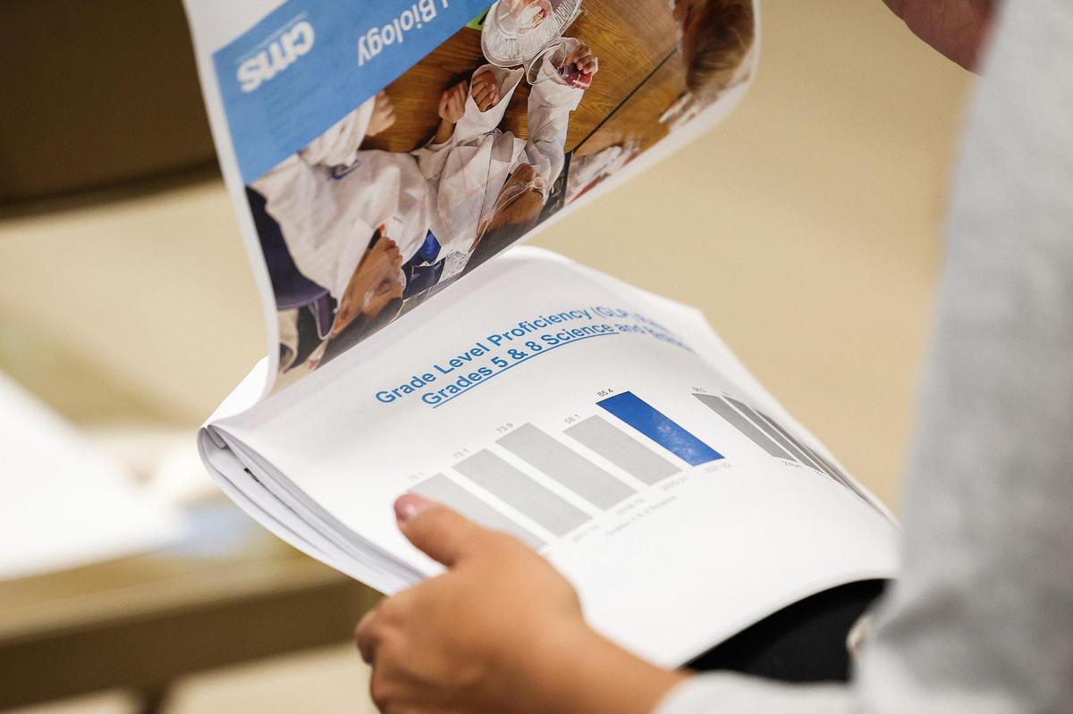 An attendee looks over a printed copy of the results of the North Carolina Department of Public Instruction 2021-2022 student academic performance data report for CMS during a press conference at Allenbrook Elementary School on Thursday.