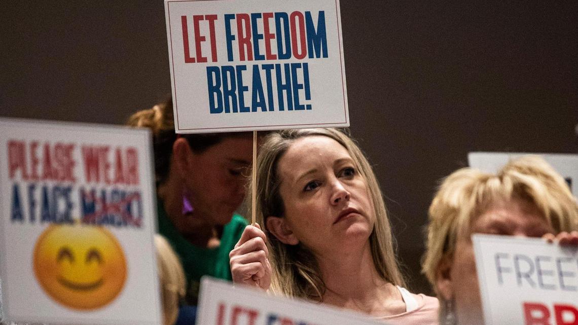 Ahead of a school board vote on Charlotte-Mecklenburg Schools’ mask mandate, attendees, including some members of Moms For Liberty, hold signs in silent protest, Feb. 22, 2022.