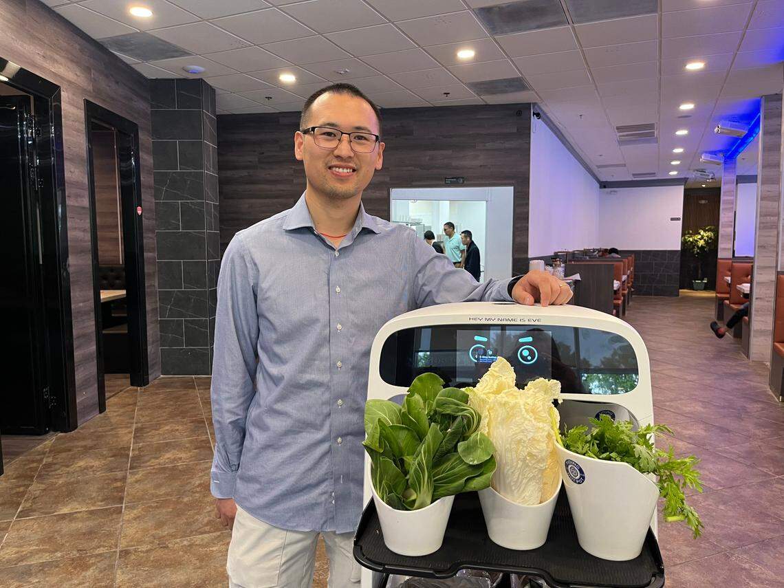 Yiding Hot Pot owner Wenda Wang shows off Eve, one of the restaurant’s two robot servers. 