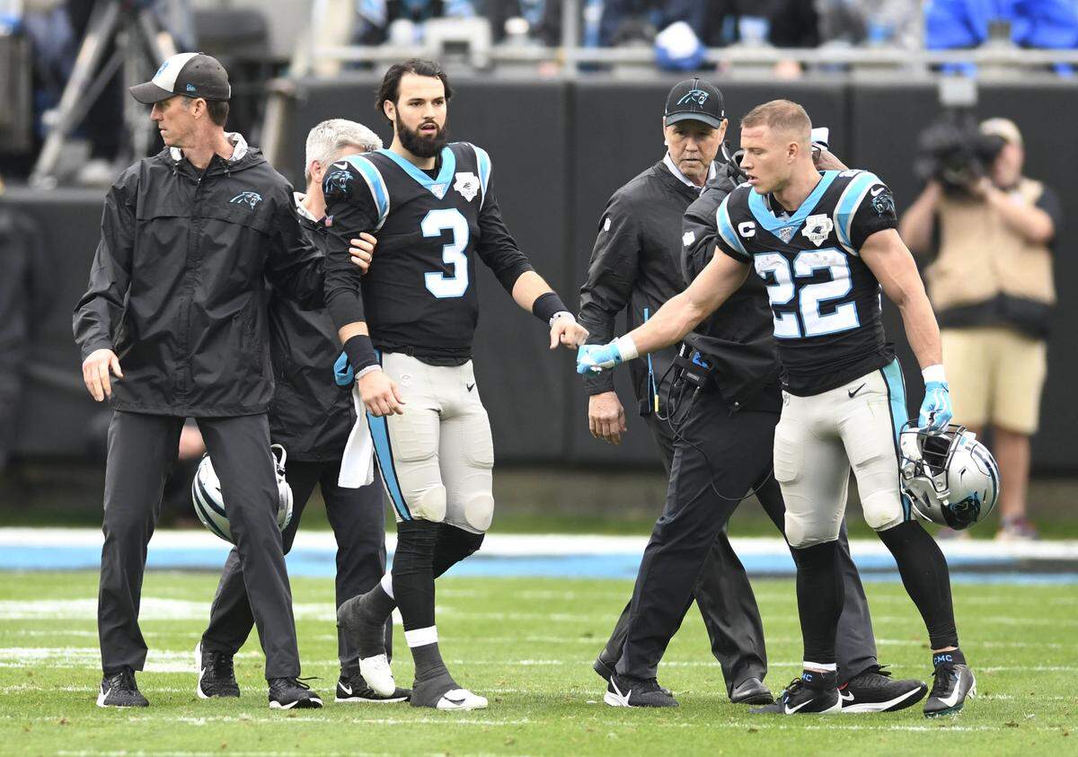Carolina Panthers quarterback Will Grier (3) is helped off the field on Dec. 29, 2019, as running back Christian McCaffrey comforts him.