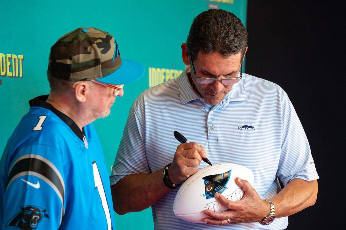 Former Charlotte Panthers head coach Ron Rivera signs a fan’s football ahead of the premiere of The Charlotte Observer’s movie ‘Supermen’ at the Independent Picture House in Charlotte, NC, Thursday July 24, 2025.