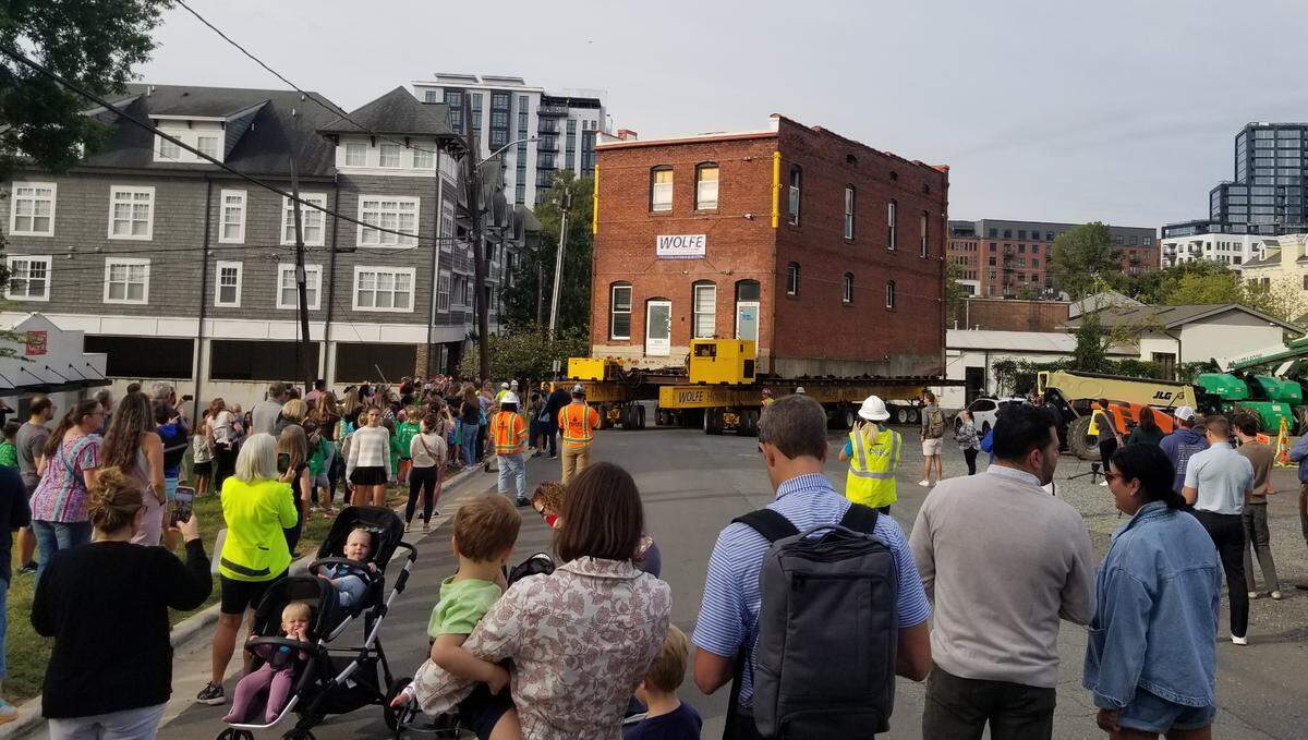 A group of residents watch as the 121-year-old Leeper & Wyatt is moved up the street in the Dilworth area in September 2024. 