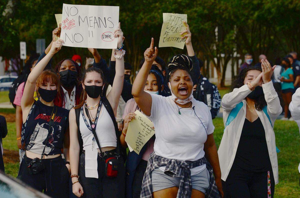 Olympic High students line both sides of Sandy Porter Road in protest outside the school on Oct. 1, 2021 in Charlotte. On Sept. 13, a 15-year-old student was charged with sexual assault of a female student. Another student, a football player, had been accused of assault and told to wear an ankle monitor. The athlete played in a recent football game wearing the monitor.