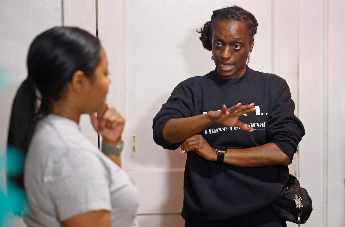 Cecilia McNeill, left, listens as K. Alana Jones, right, gives her instruction on a dance during an immersive play on gentrification. McNeill and Jones joined others for play rehearsal on Tuesday, August 13, 2024 at the QC Family Tree’s Big Blue House in Charlotte, NC.