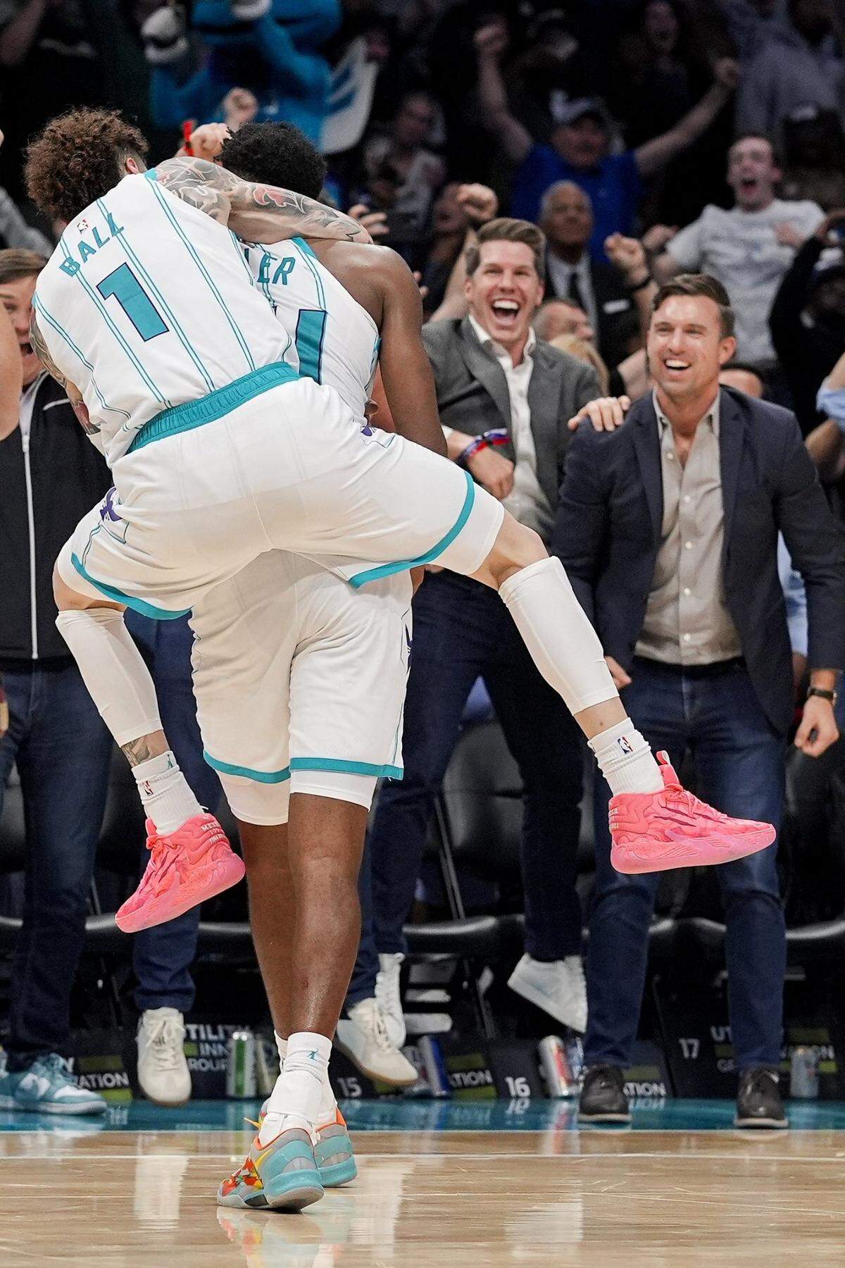 Fans react as Charlotte Hornets guard LaMelo Ball (1) jumps on the back of forward Brandon Miller (24) after his final second put back wins the game against the Detroit Pistons during the second half at Spectrum Center.