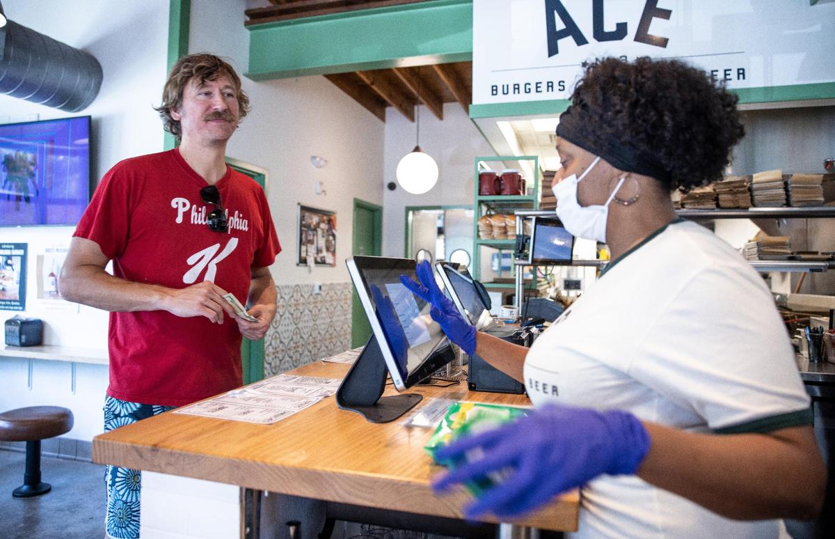 Justin Rawling, left, places an order Thursday from Ace No. 3 employee Ebony Miller. The Charlotte restaurant requires staff to wear masks while customers follow the new guideline to unmask if vaccinated or mask if not.