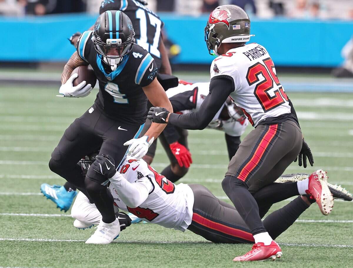 Carolina Panthers wide receiver Tetairoa McMillan, left, turns to pick up yardage following a pass reception as Tampa Bay Buccaneers defenders look to make the tackle during action on Sunday, Dec. 21, 2025, at Bank of America Stadium in Charlotte. The Panthers defeated the Buccaneers 23-20.