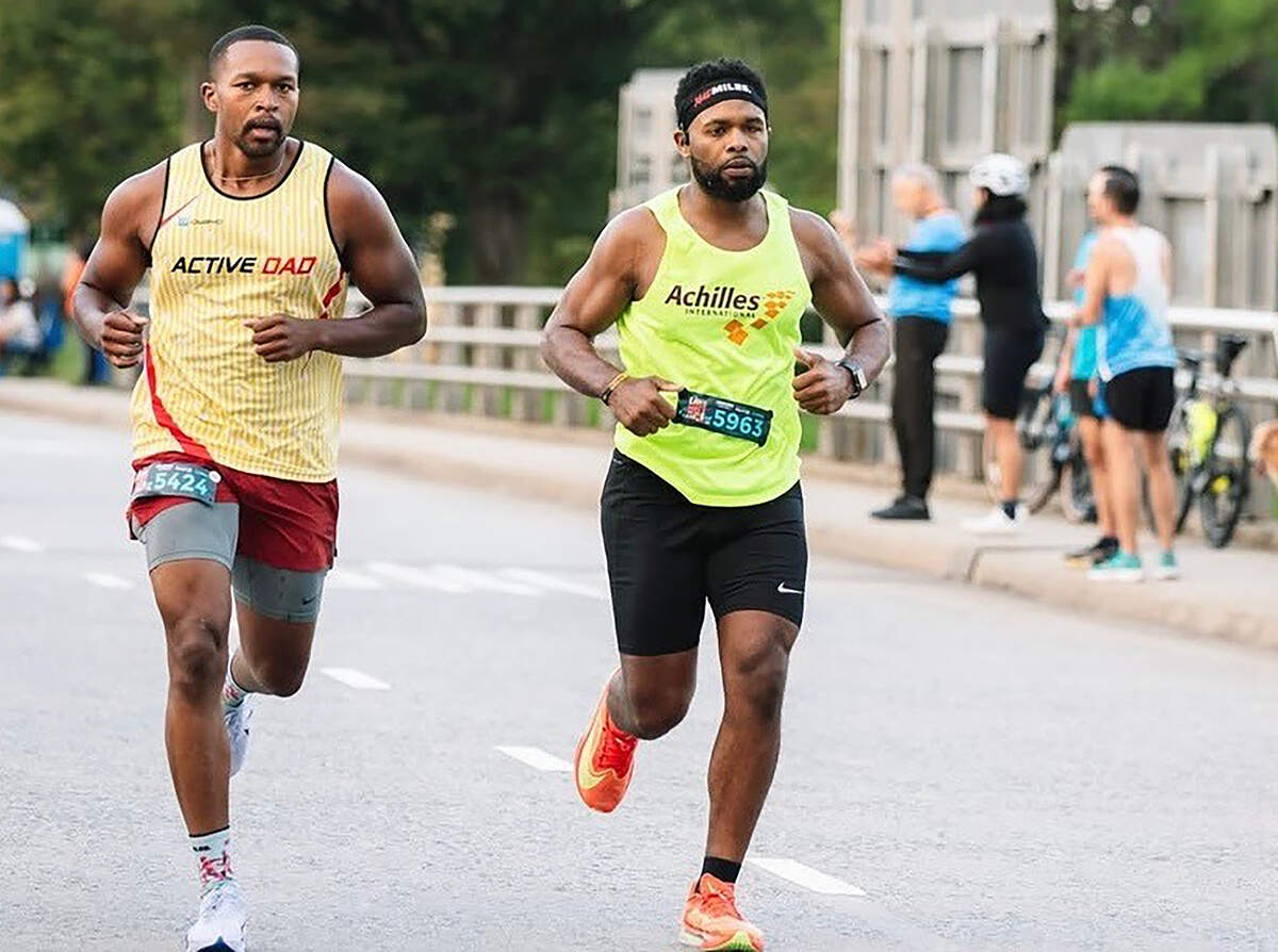 Tevin Price, right, runs alongside his friend and guide Isa Moore at the Around the Crown 10K in Charlotte this past Aug. 31. In certain situations, Price will run untethered, though he admits that it was probably a mistake to do so during the final miles of his first marathon attempt in Virginia.