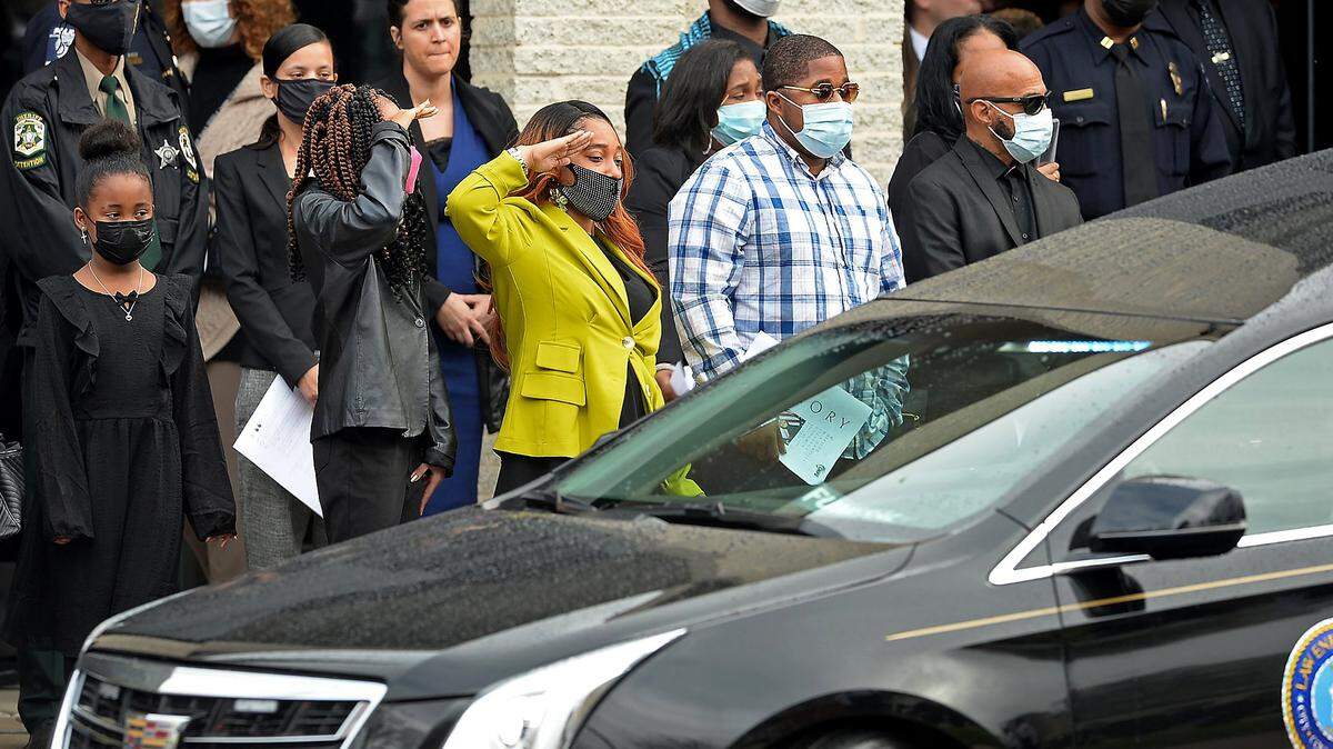 Two mourners salute CMPD Officer Mia Goodwin as the hearse leaves First Baptist Church in Charlotte, NC on Wednesday, December 29, 2021. Officer Goodwin was killed while responding to a crash on Interstate 85 on December 22, 2021.