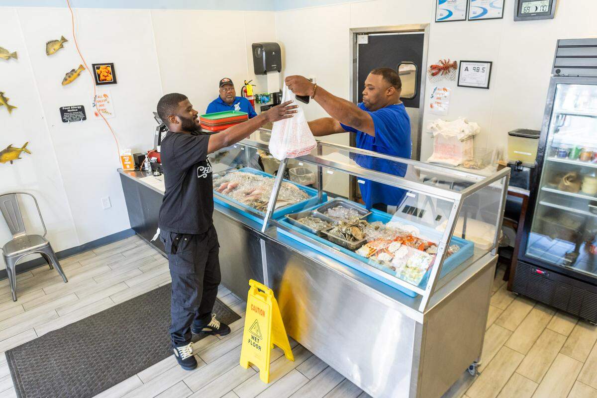 Big Wayne Bryan and owner LJ Bryant give a guest his order at Bryant Seafood Market.