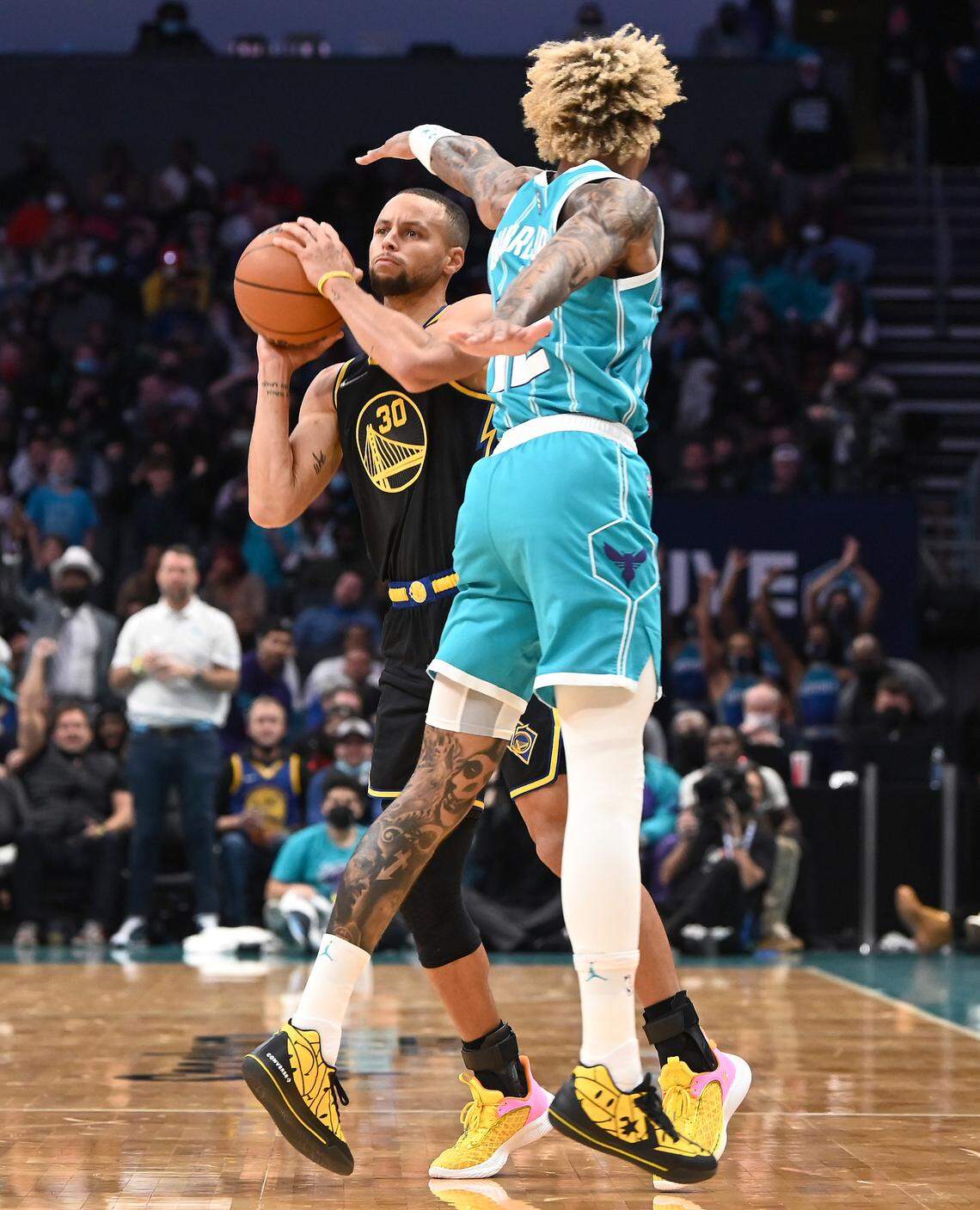 Golden State Warriors guard Stephen Curry, left, tries a difficult shot Sunday against the defense of Charlotte’s Kelly Oubre Jr.