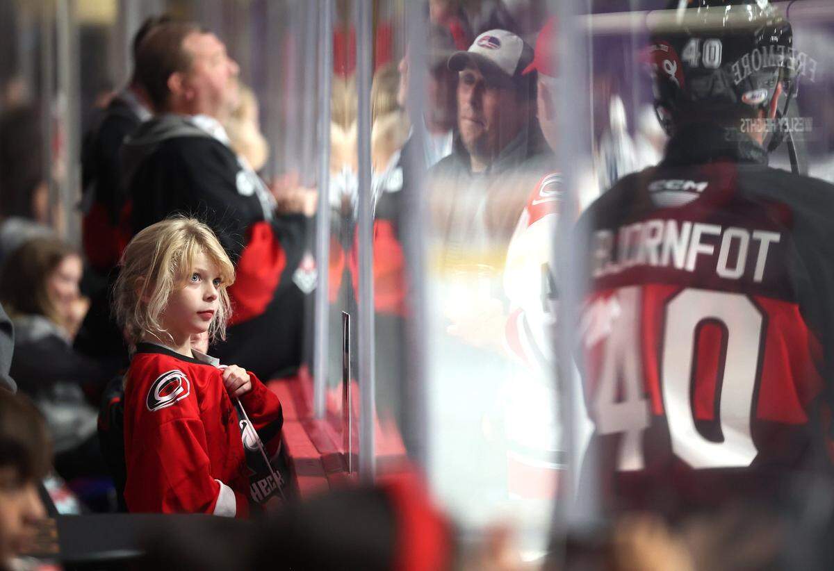 Charlotte Checkers fan Riley Wilson, left, watches as members of the team skate past during a warmup prior to action against the Cleveland Monsters at Bojangles Coliseum in Charlotte, NC on Friday, October 18, 2024.