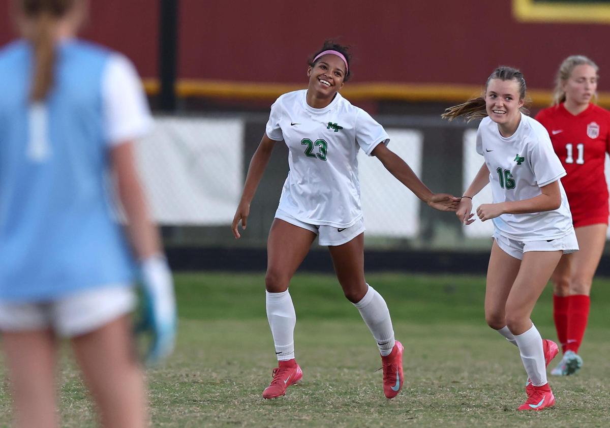 Myers Park’s Amaya Falzarano, center, smiles as she is congratulated by teammate Laine Connell, right, following a goal against South Meck during action on Tuesday, May 6, 2025. Myers Park defeated South Meck 2-1.