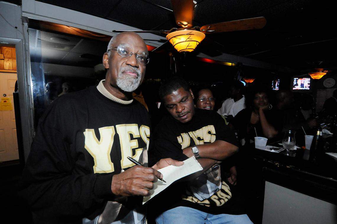 James Ferguson (left) and Karl Sims (right) check the returns from the TV while at an election party at The Historic Excelsior Club on Tuesday night. DAVID T. FOSTER III-dtfoster@charlotteobserver.com
