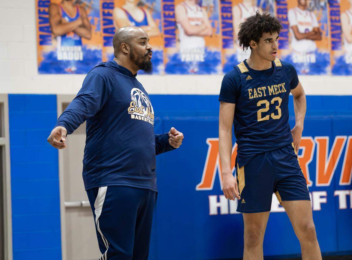 East Meck head basketball coach Joseph Gripper (left) discusses an offensive play with Jordan Buzzard (right) during West Meck free throws. West Meck Men's basketball team would take on East Meck at the Phenom Hoops Mike Gminski Classic at Marvin Ridge High School December 27, 2025.