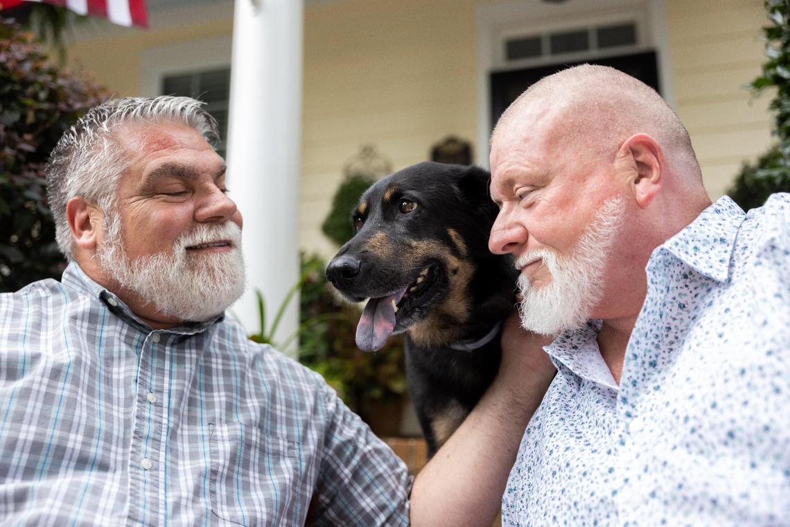John Winn, left, and Steve Nichols sit on their front door step with their new dog, Oscar, in Indian Trail. Steve and John adopted Oscar after learning about how his previous owners thought the dog was gay.