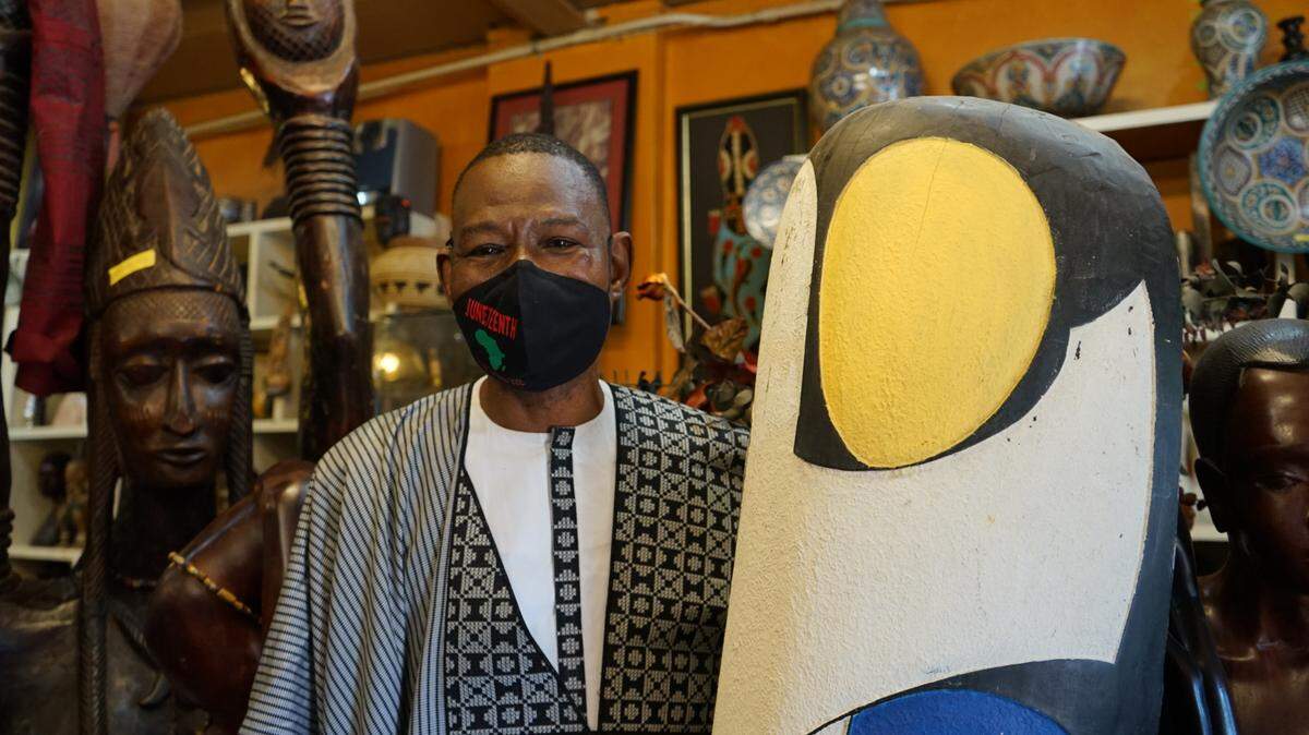 Pape Ndiaye next to an African mask at House of Africa.