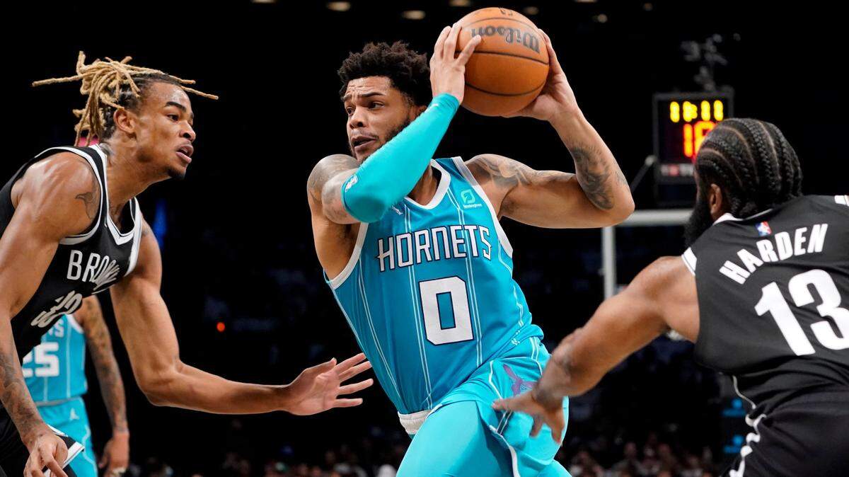 Charlotte Hornets forward Miles Bridges (0) drives past Brooklyn Nets guard James Harden (13) and forward Nic Claxton (33) on Sunday in Brooklyn. Bridges had 32 points in the Hornets’ 111-95 victory.