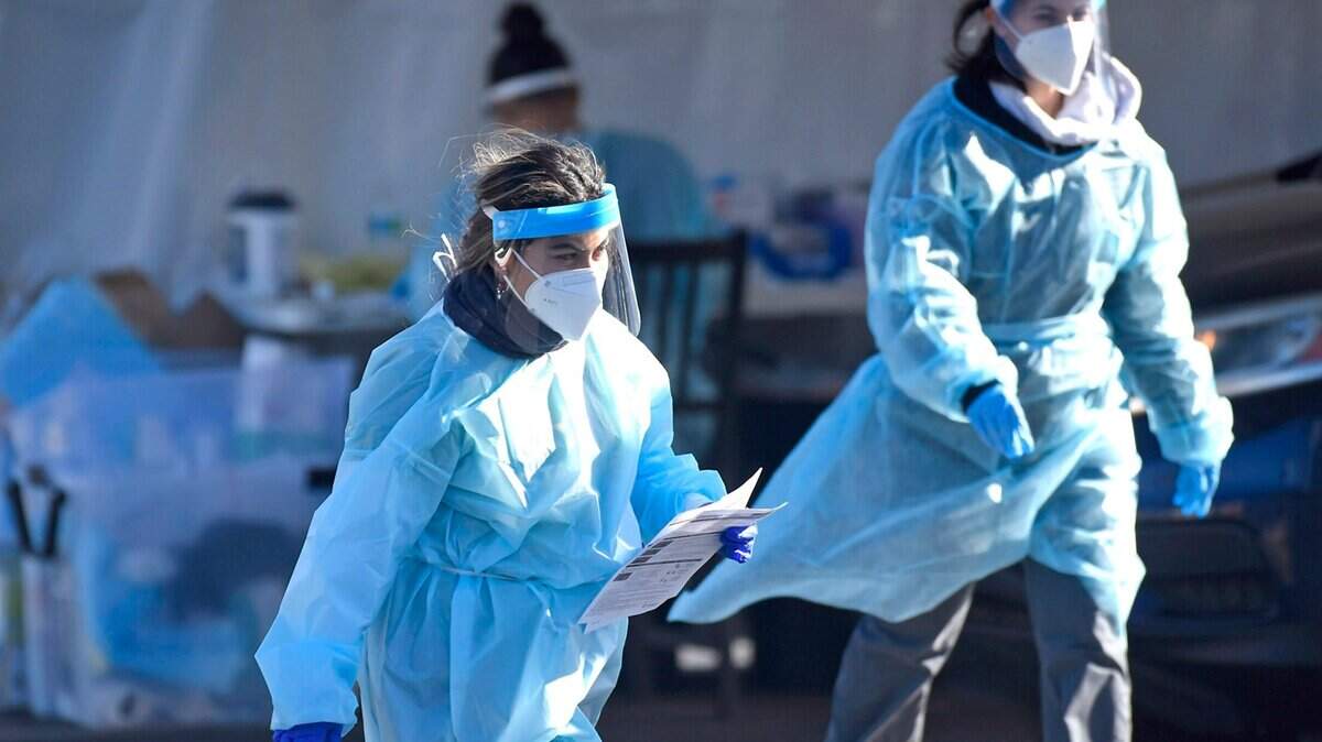 Healthcare workers prepare to collect and gather information from persons wanting a COVID-19 test.