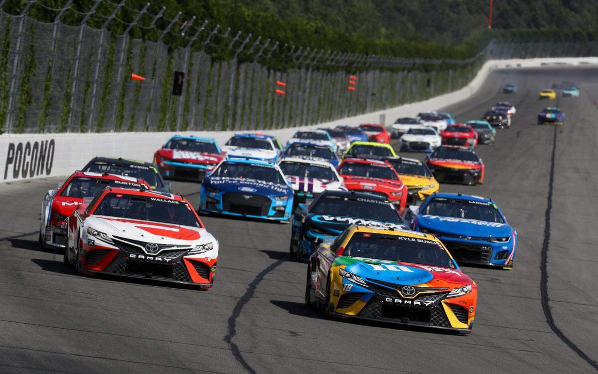 Jul 24, 2022; Long Pond, Pennsylvania, USA; NASCAR Cup Series driver Kyle Busch (18) leads the field during the M&MÕS Fan Appreciation 400 at Pocono Raceway. Mandatory Credit: Matthew OHaren-USA TODAY Sports