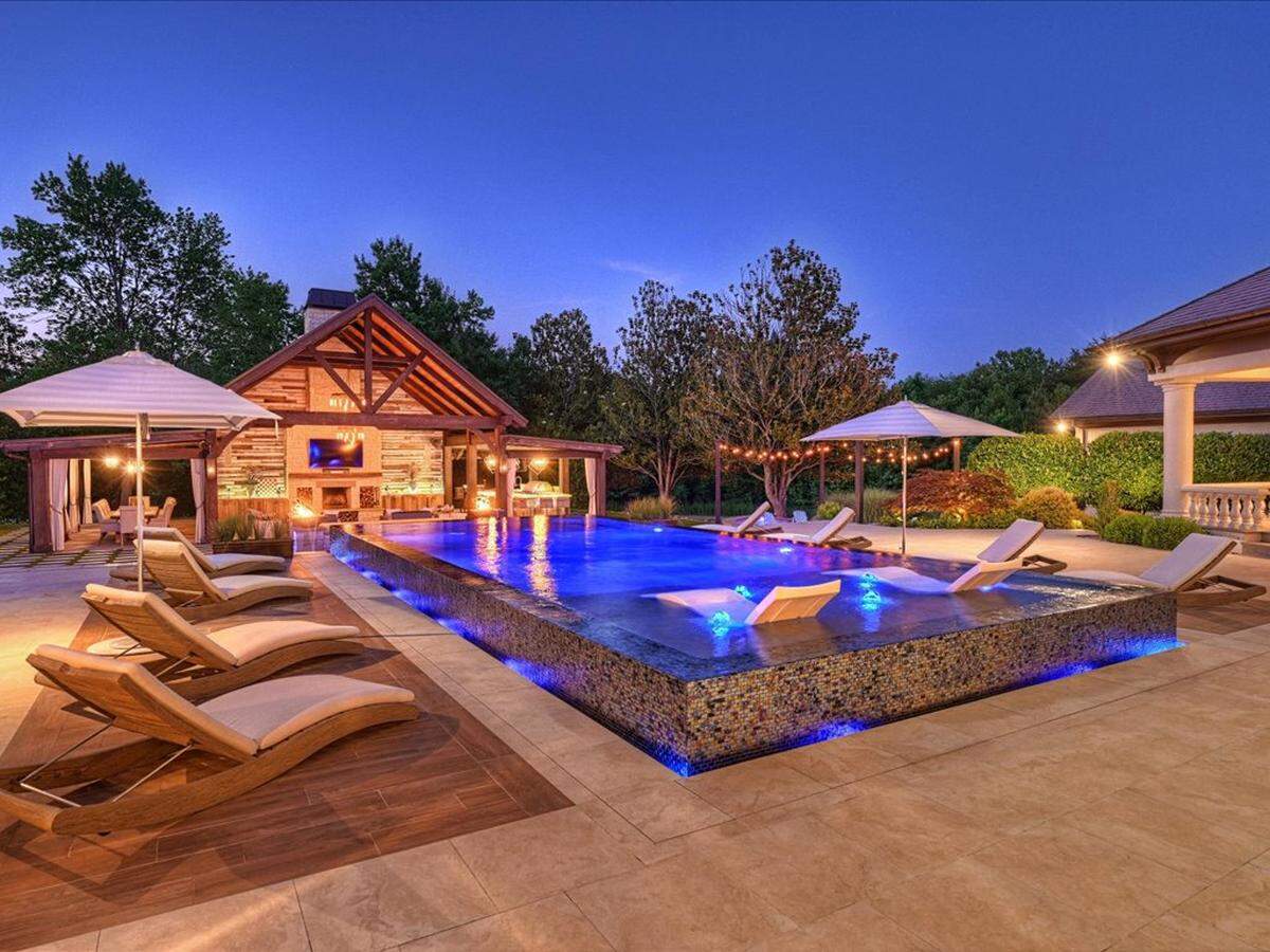 The pool in the backyard of the mansion is shown at twilight.