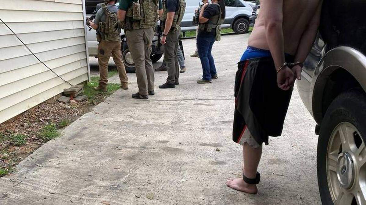 In this undated image from Observer news partner WSOC, a fugitive suspect waits after he is arrested by a U.S. Marshals Service task force. The service and Charlotte-area law enforcement said on Wednesday, July 20, 2022, that 91 violent-crime suspects have been arrested in a multi-agency sweep across Gaston County and York County, S.C.