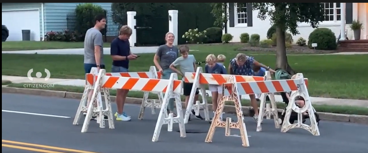Neighbors peering into a small sinkhole forming on Providence Road. Video was posted Tuesday evening on the app Citizen.