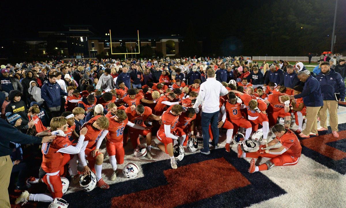 The Providence Day Chargers kneel in prayer with head coach Chad Grier following their 14-9 victory over Rabun Gap at Providence Day School in Charlotte, NC on Friday, November 19, 2021. The Chargers defeated Rabun Gap to win the NCISAA boys state championship game.