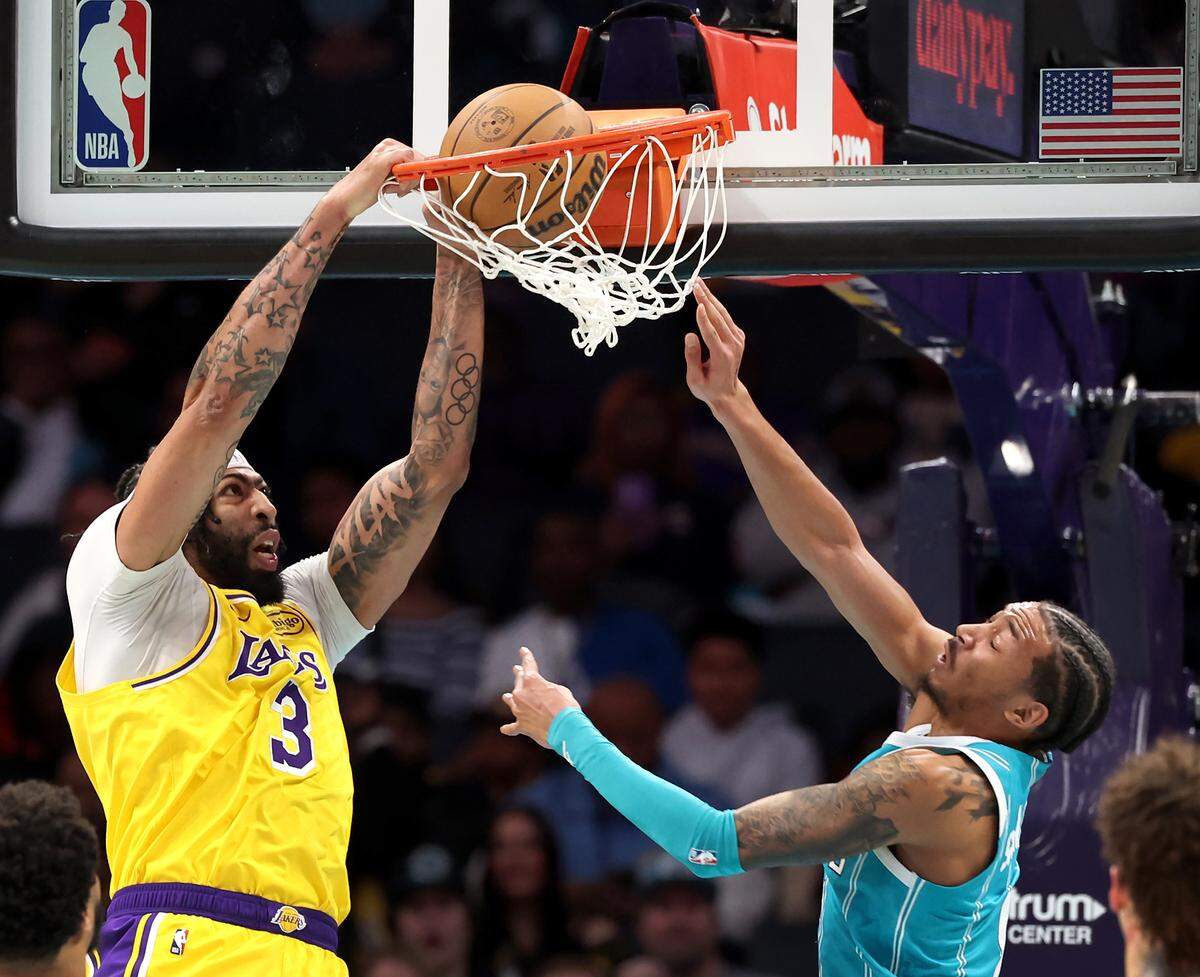 Los Angeles Lakers center Anthony Davis, left, throws down a two-handed dunk as Charlotte Hornets guard Nick Smith Jr., right, attempts to stop the play during action at Spectrum Center in Charlotte, NC on Monday, January 27, 2025.