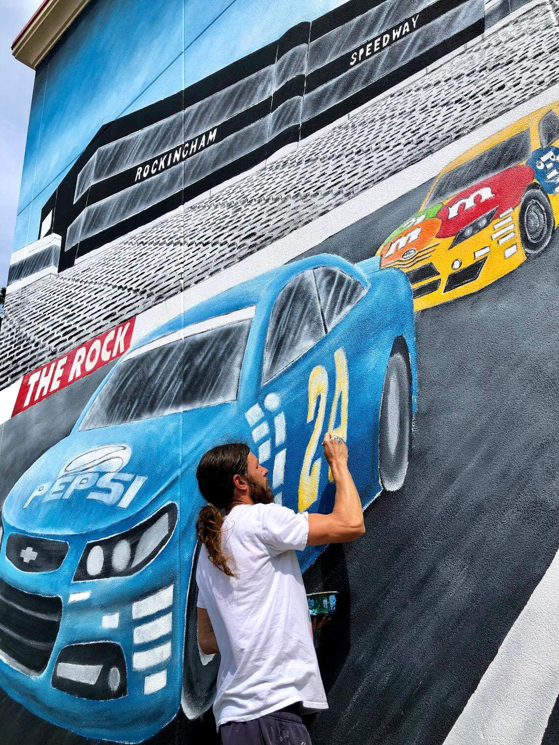 Local Rockingham, NC artist Daniel Evan Webb puts the final touches on a wall mural he has been painting at the Corner Cupboard Food Stores along Hwy 74 on Saturday, April 19, 2025. NASCAR has returned to Rockingham Speedway with the running of the ARCA Menards Series East 125 race and the North Carolina Education Lottery 250 on Saturday.