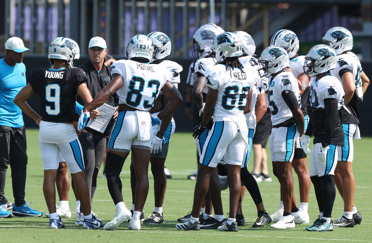 Carolina Panthers offensive coordinator Brad Idzik, left/facing camera, speaks with quarterback Bryce Young and members of the team’s wide receiver corp following a series of drills during the team’s training camp practice on Wednesday, July 29, 2026.