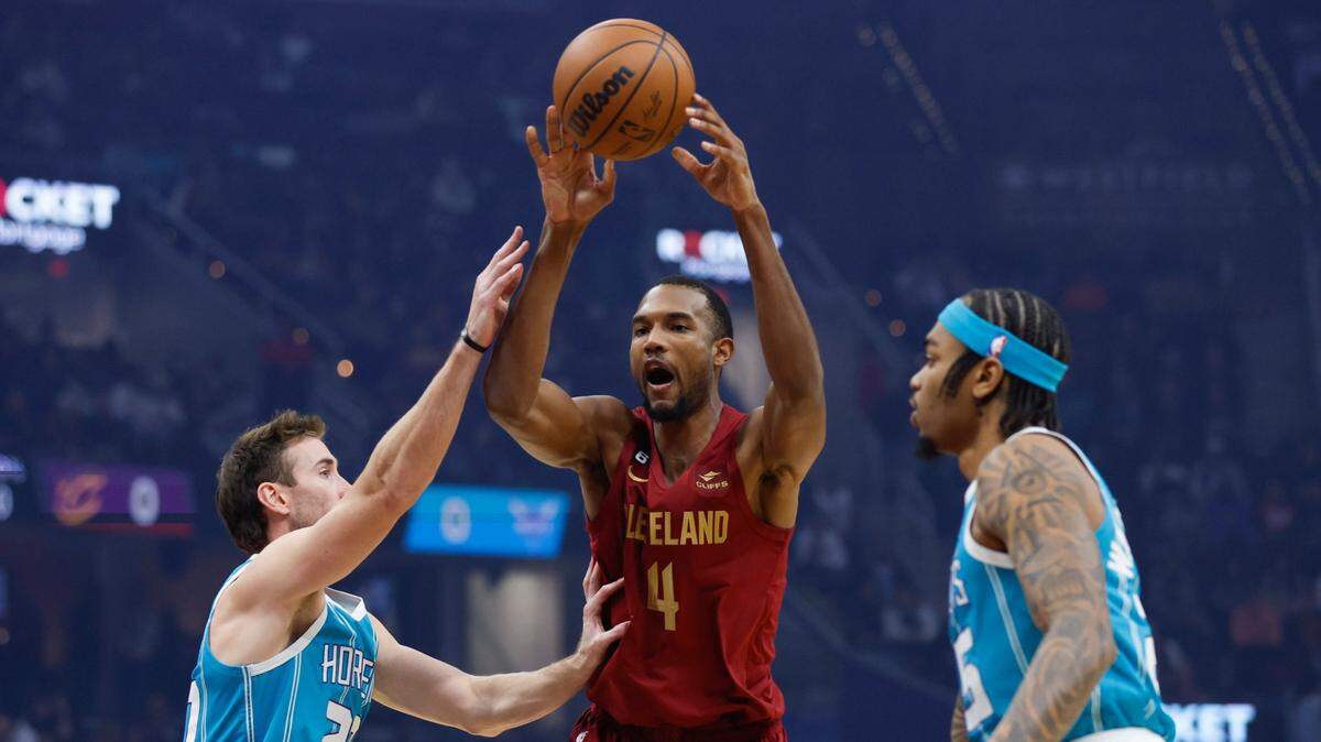 Cleveland Cavaliers forward Evan Mobley (4) passes the ball from between Charlotte Hornets forwards Gordon Hayward (20) and P.J. Washington (25) during the first half of an NBA basketball game Friday, Nov. 18, 2022, in Cleveland. (AP Photo/Ron Schwane)