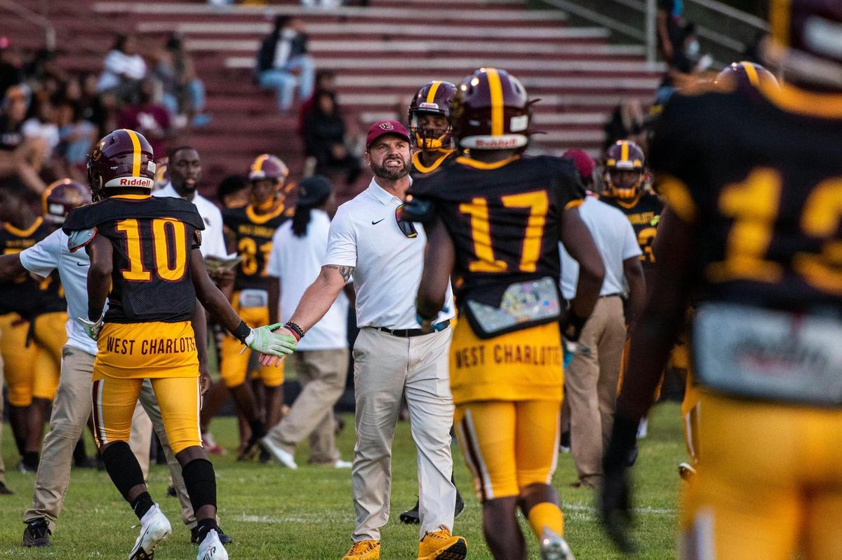 West Charlotte head coach Sam Greiner, center, congratulates the defense after they prevented Harding University from scoring during the game on Friday, August 27, 2021 in Charlotte, NC.