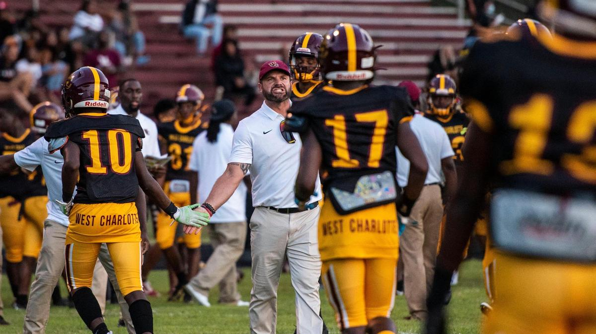 West Charlotte head coach Sam Greiner, center, congratulates the defense after they prevented Harding University from scoring during the game on Friday, August 27, 2021 in Charlotte, NC.