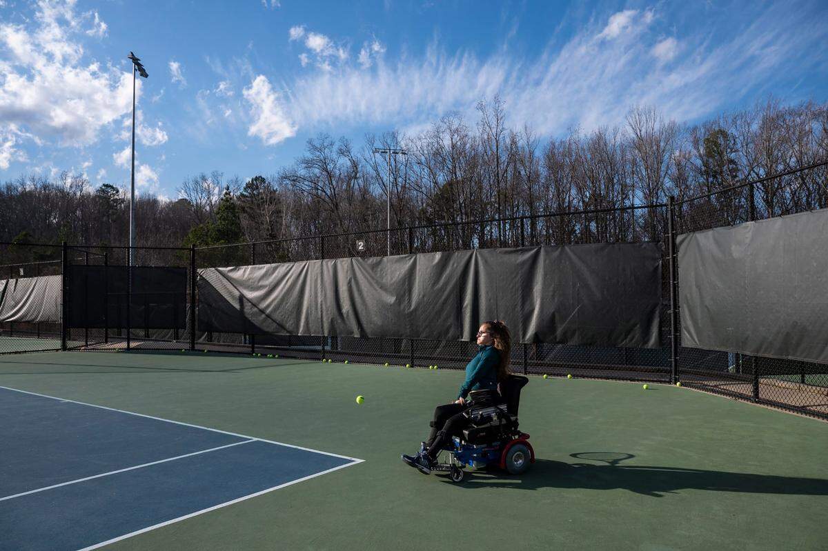 Wheelchair tennis player Gaila Fosbinder practices with her coach at Queens Tennis Center in Marion Diehl Park on Friday, February 25, 2022 in Charlotte, NC. Fosbinder was born with a medical condition called arthrogryposis that malformed her limbs and makes her unable to form muscle mass. She uses a motorized chair that allows her to maneuver around the court.